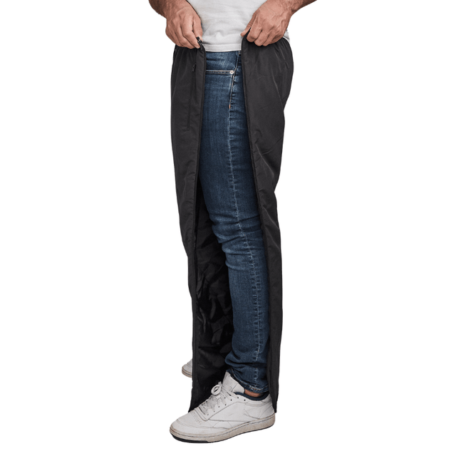 Mann öffnet schwarze Dobsom Thermohose seitlich über blauen Jeans und weißen Turnschuhen