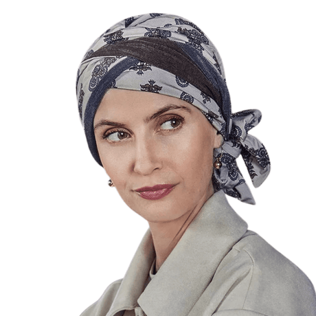 Vrouw draagt Beatrice tulband met paisley-patroon in beige, bruin en blauw, aan de zijkant geknoopt