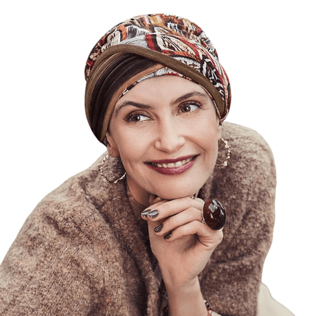 Glimlachende vrouw draagt Shakti tulband met Tribal Feathers verenprint in warme herfstkleuren