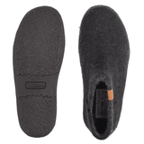 Twee zwarte Green Comfort pantoffels van wolvilt, de ene toont de antislip rubberen zool, de andere de bovenkant